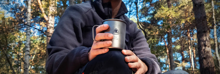 Person holding a lightweight, titanium Robens Mug with a woodland background
